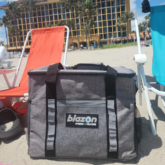 Gray Blazon Hybrid Heaters cooler bag on sandy beach between orange and blue beach chairs