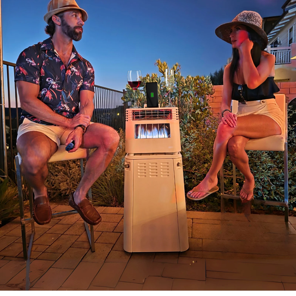 Man and woman sitting on patio chairs around a beige outdoor heater with drinks at dusk