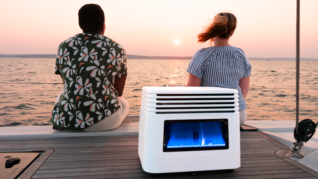 Two people sitting on a boat deck at sunset with a portable white heater glowing blue