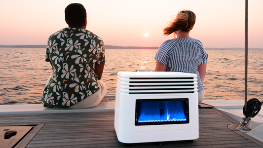 Two people sitting on a boat deck at sunset with a portable white heater glowing blue