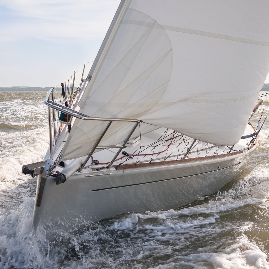 A sailboat cuts through frothy seas
