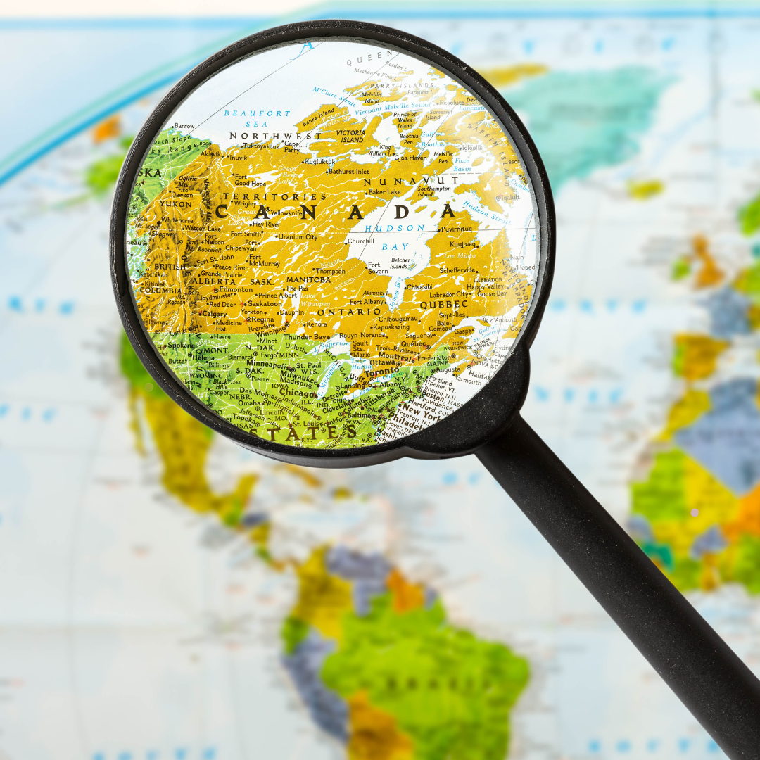 Magnifying glass focusing on a colorful map highlighting Canada, the United States, and parts of the Arctic