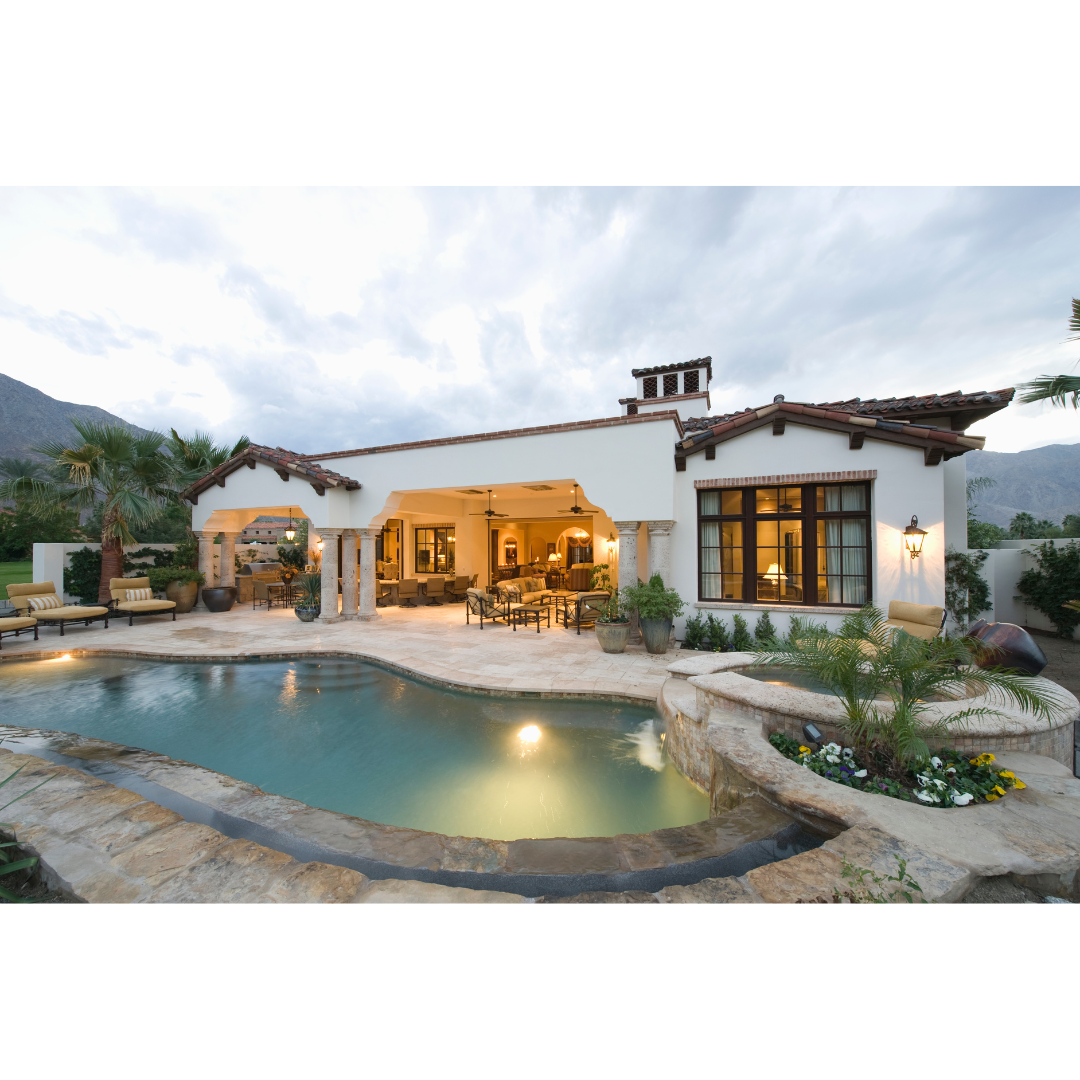 Luxury Spanish-style home with tiled roof, outdoor pool, hot tub, and patio seating at dusk