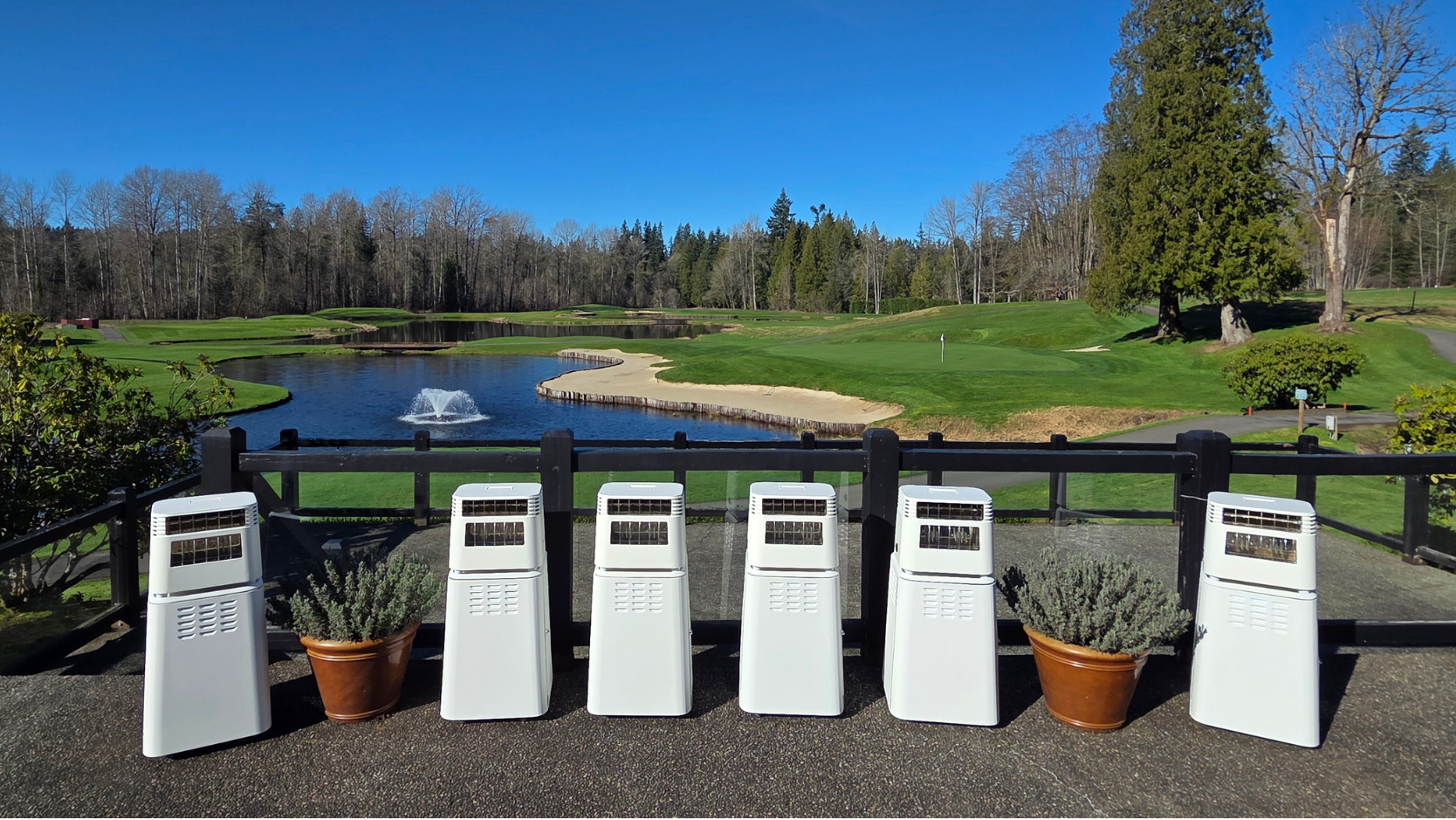 Row of air conditioners on a patio with a scenic golf course background