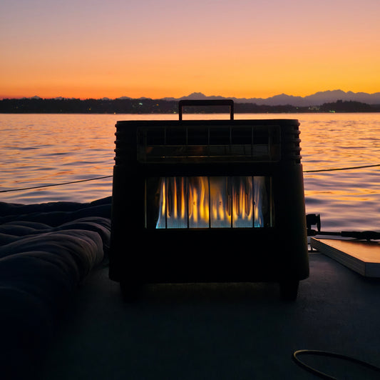 Outdoor gas heater on a dock at sunset by a calm lake with mountains in the background